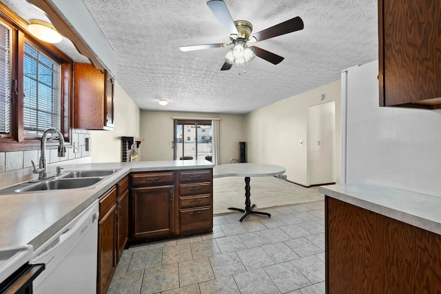 kitchen with ceiling fan, stove, kitchen peninsula, sink, and white dishwasher