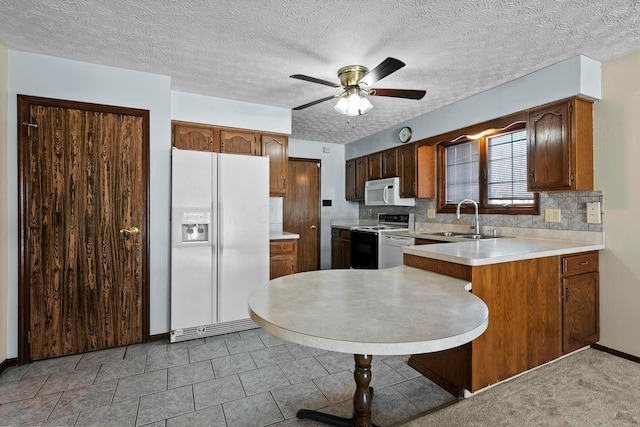 kitchen featuring ceiling fan, kitchen peninsula, decorative backsplash, sink, and white appliances