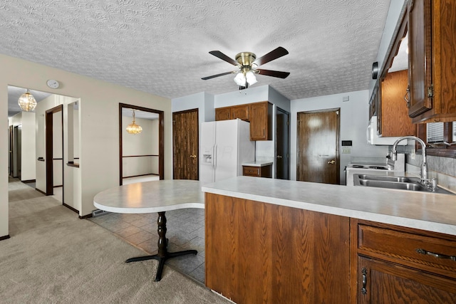 kitchen with white fridge with ice dispenser, a textured ceiling, sink, ceiling fan, and light colored carpet