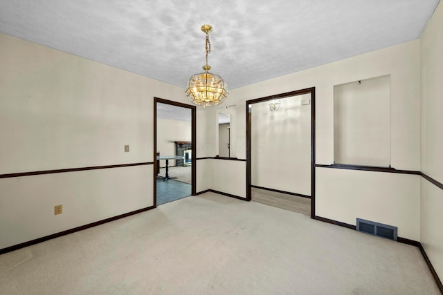 carpeted empty room featuring a chandelier