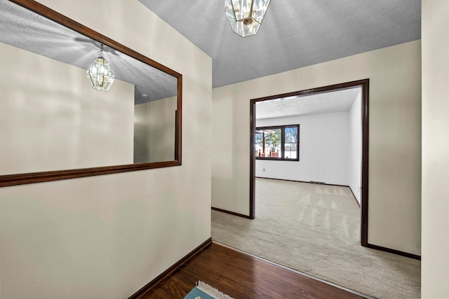 hallway with wood-type flooring, a notable chandelier, and a textured ceiling