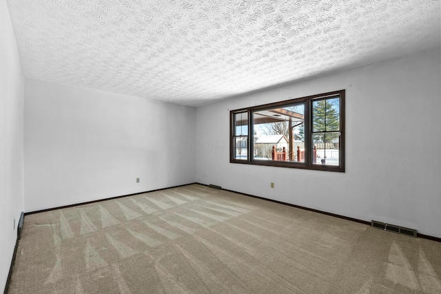 spare room with light carpet and a textured ceiling