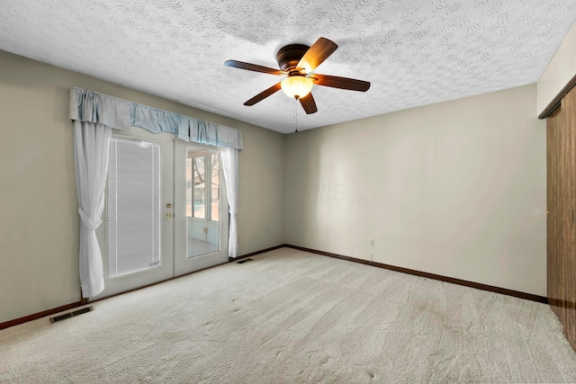 carpeted spare room with ceiling fan, a textured ceiling, and french doors