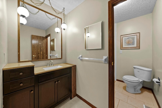 bathroom with a textured ceiling, toilet, tile patterned floors, and vanity