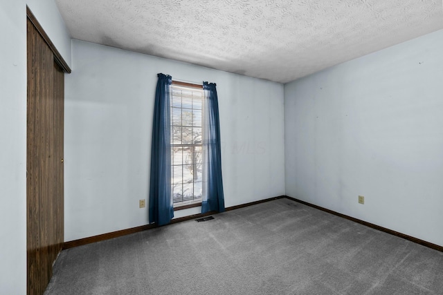 carpeted empty room featuring a textured ceiling