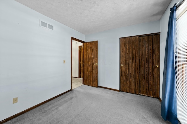 unfurnished bedroom with light colored carpet, a textured ceiling, and a closet