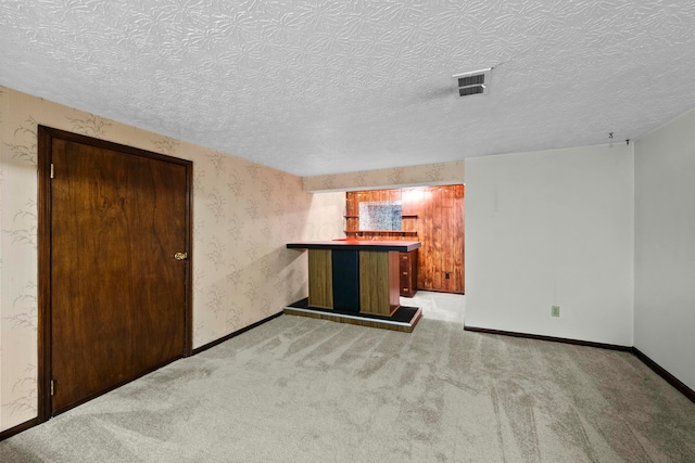 carpeted spare room featuring indoor bar and a textured ceiling