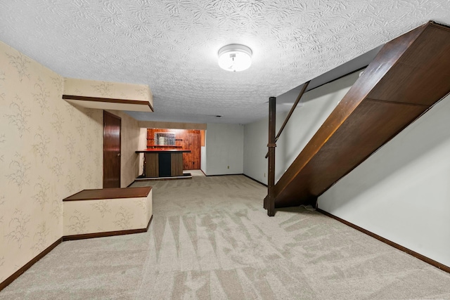 basement featuring a textured ceiling and light colored carpet