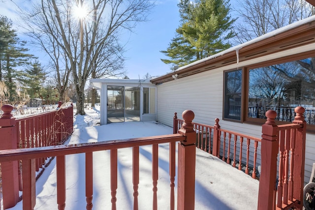 snow covered deck featuring a sunroom