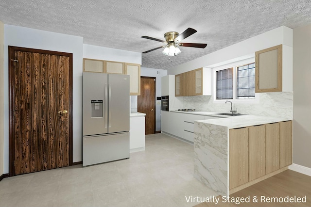 kitchen featuring tasteful backsplash, ceiling fan, sink, light brown cabinets, and stainless steel fridge