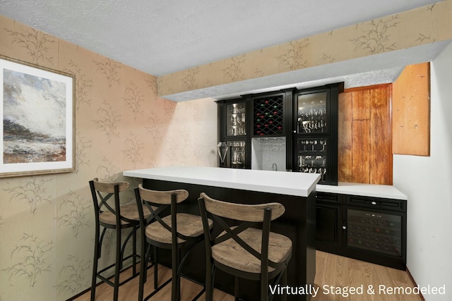 bar featuring light hardwood / wood-style floors and a textured ceiling