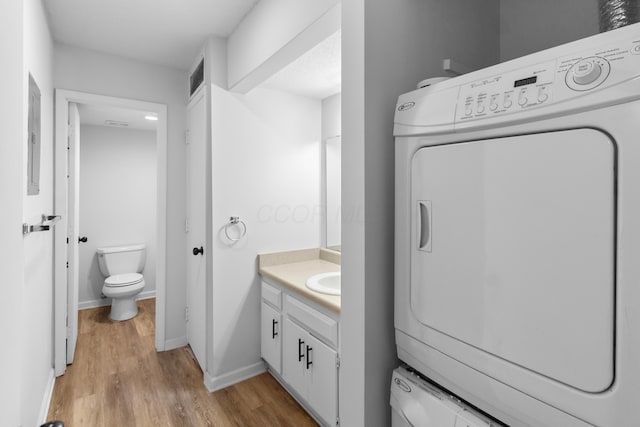 bathroom featuring vanity, toilet, stacked washing maching and dryer, and wood-type flooring