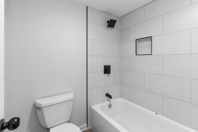 bathroom with tiled shower / bath combo and toilet