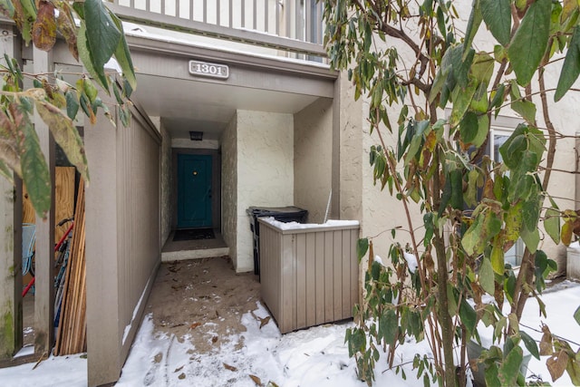 snow covered property entrance with a balcony