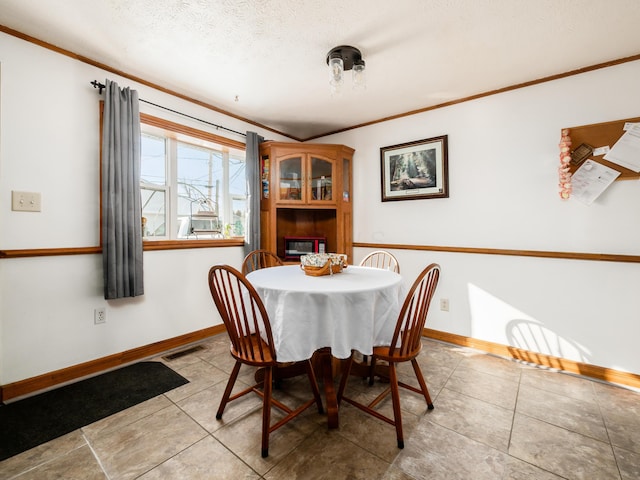 tiled dining area featuring a textured ceiling and ornamental molding