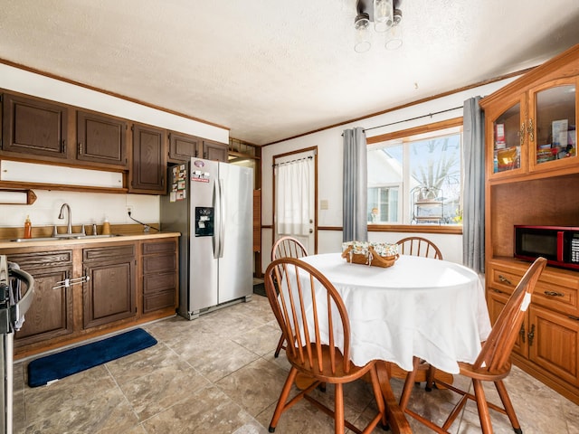 dining area with a textured ceiling, ornamental molding, and sink