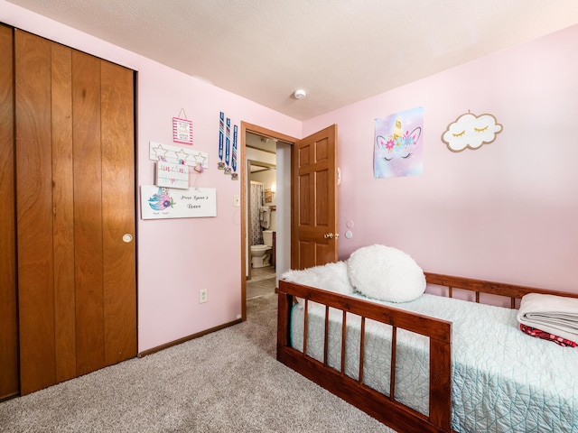 carpeted bedroom featuring ensuite bathroom and a closet