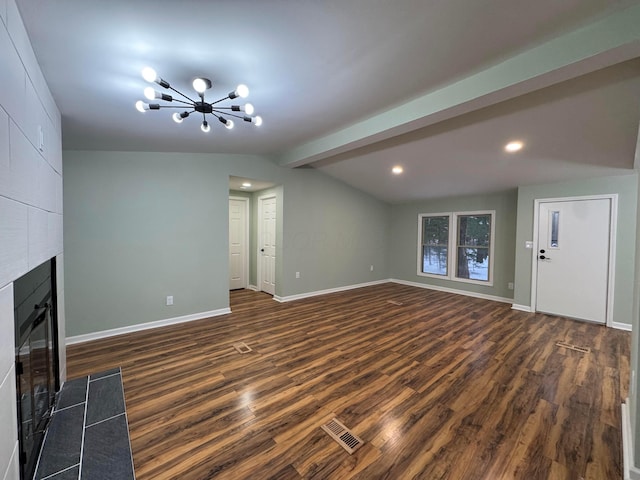 unfurnished living room featuring a tiled fireplace, dark hardwood / wood-style flooring, lofted ceiling with beams, and an inviting chandelier