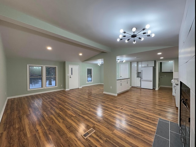 unfurnished living room with lofted ceiling with beams, dark hardwood / wood-style flooring, a chandelier, and a tiled fireplace