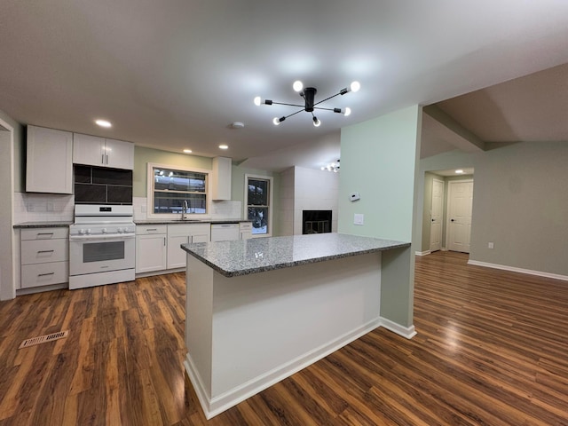 kitchen with kitchen peninsula, decorative backsplash, white appliances, sink, and white cabinetry