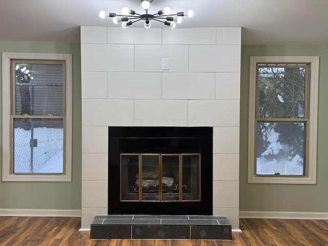 room details with an inviting chandelier, wood-type flooring, and a tiled fireplace