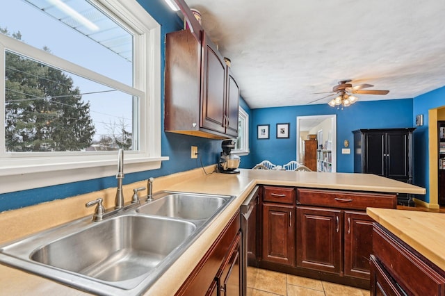 kitchen with kitchen peninsula, ceiling fan, sink, and light tile patterned flooring