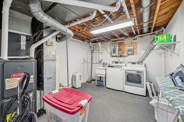 basement with heating unit, electric panel, washer and clothes dryer, and sink