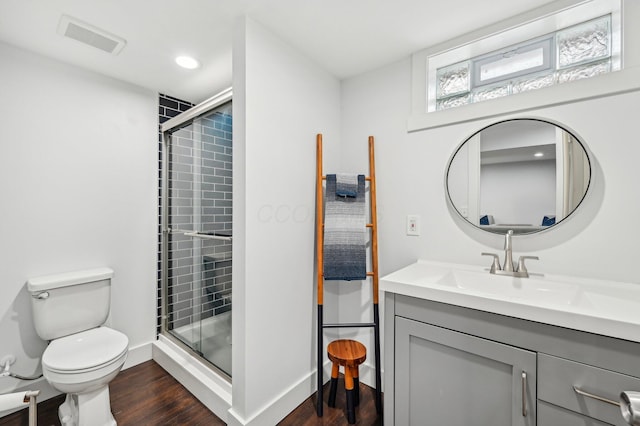 bathroom featuring hardwood / wood-style floors, vanity, toilet, and a shower with door