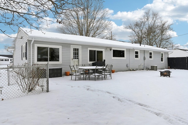 snow covered rear of property with cooling unit and an outdoor fire pit