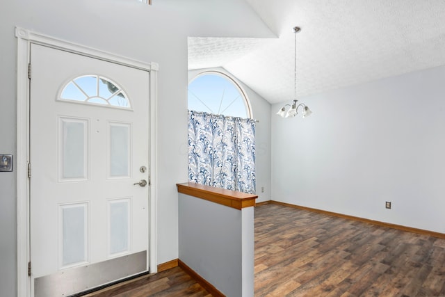 foyer entrance featuring a notable chandelier, lofted ceiling, a textured ceiling, and dark wood-type flooring