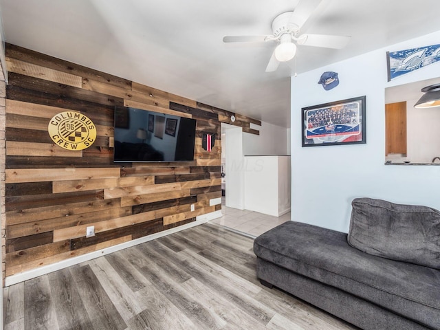 living room featuring hardwood / wood-style flooring, ceiling fan, and wooden walls