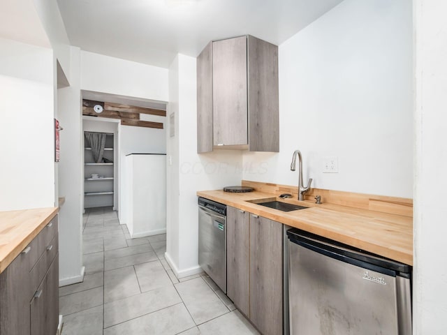 kitchen featuring wood counters, dishwasher, sink, light tile patterned floors, and fridge