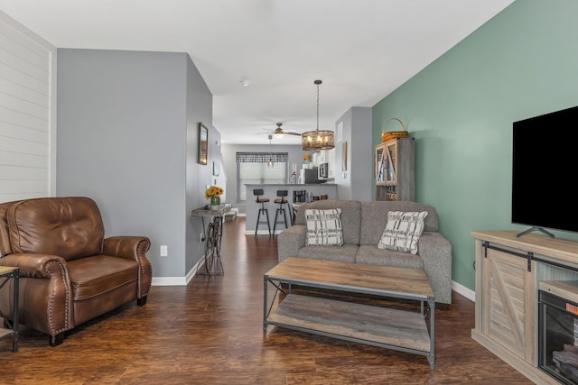 living room with ceiling fan with notable chandelier and dark hardwood / wood-style floors