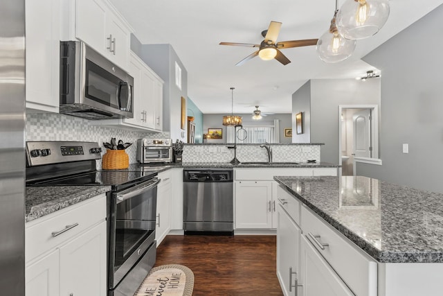 kitchen with white cabinetry, ceiling fan, appliances with stainless steel finishes, dark stone countertops, and sink