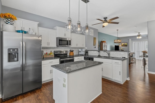 kitchen featuring kitchen peninsula, stainless steel appliances, decorative backsplash, white cabinets, and a center island