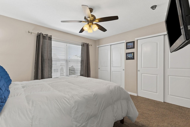 carpeted bedroom with ceiling fan and two closets