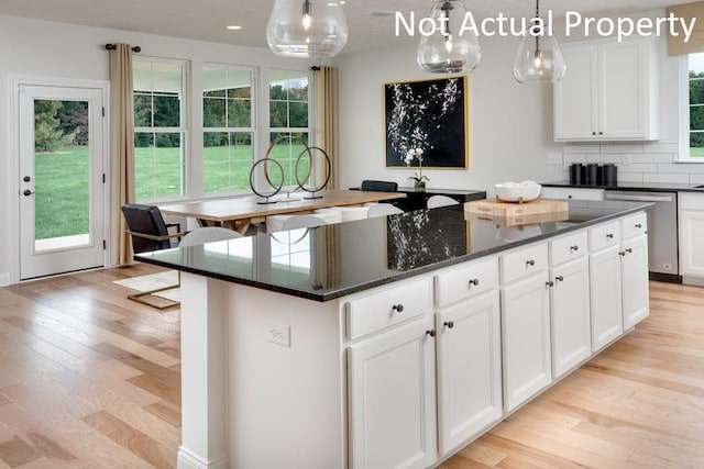 kitchen featuring stainless steel dishwasher, a center island, hanging light fixtures, and white cabinets