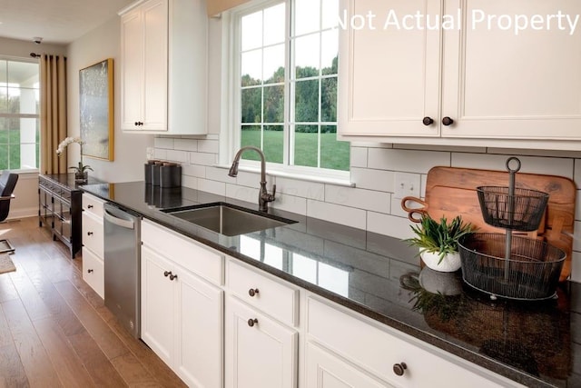 kitchen featuring sink, dark stone countertops, dishwasher, a healthy amount of sunlight, and white cabinets