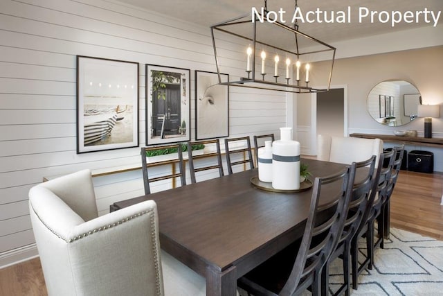 dining area with an inviting chandelier, hardwood / wood-style floors, and wood walls