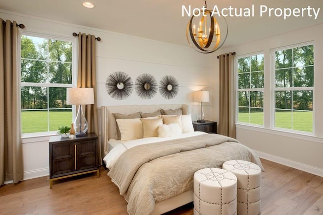 bedroom featuring multiple windows, a notable chandelier, and light hardwood / wood-style floors