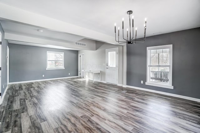 interior space with dark wood-type flooring, a chandelier, and a healthy amount of sunlight