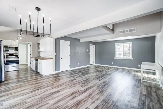 unfurnished living room featuring wood-type flooring, a notable chandelier, and sink