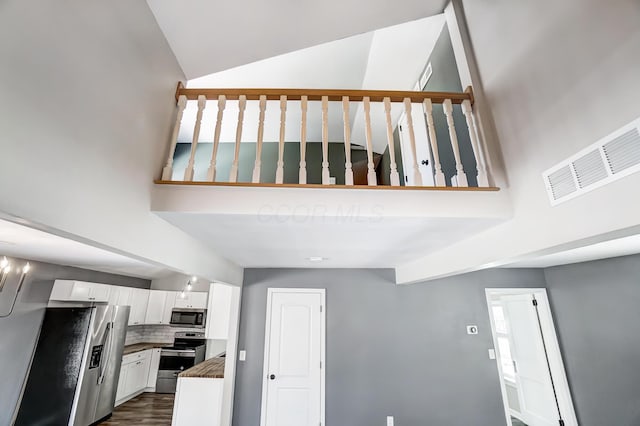 interior space featuring lofted ceiling, white cabinets, stainless steel appliances, and tasteful backsplash