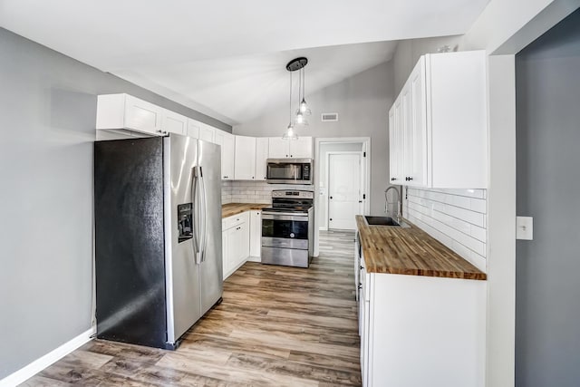 kitchen featuring sink, butcher block countertops, appliances with stainless steel finishes, and white cabinets