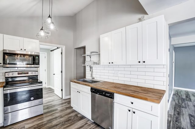 kitchen featuring white cabinets, appliances with stainless steel finishes, decorative light fixtures, sink, and high vaulted ceiling