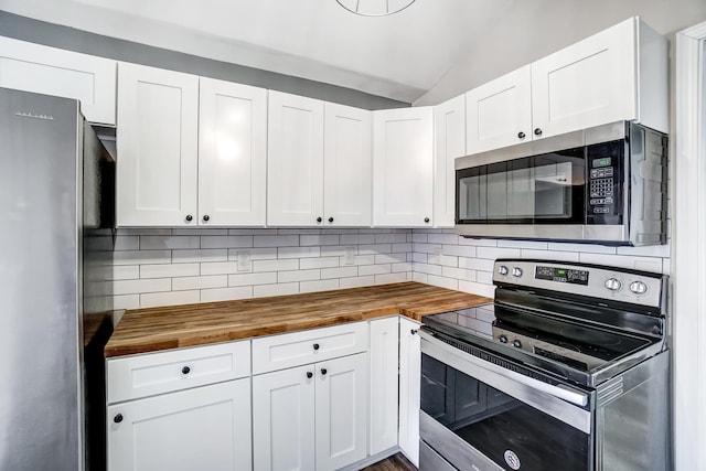 kitchen with appliances with stainless steel finishes, butcher block counters, and tasteful backsplash