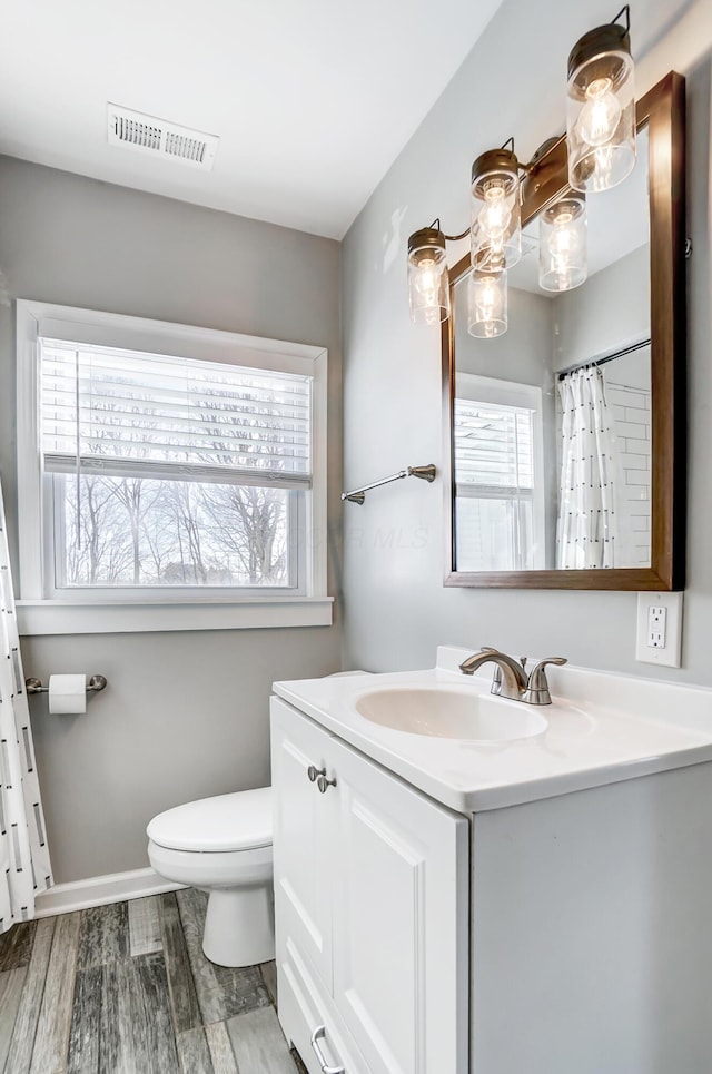 bathroom with hardwood / wood-style floors, toilet, vanity, and a wealth of natural light