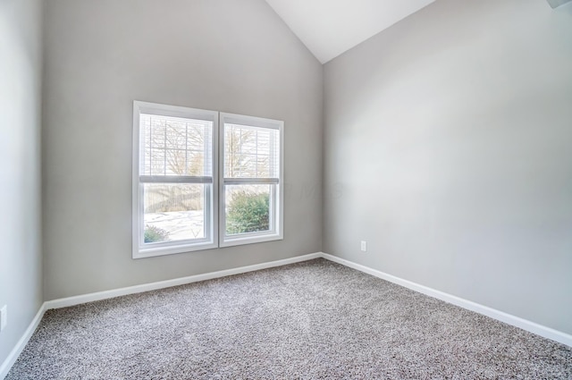 carpeted spare room with high vaulted ceiling