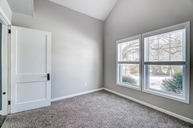 carpeted spare room with vaulted ceiling