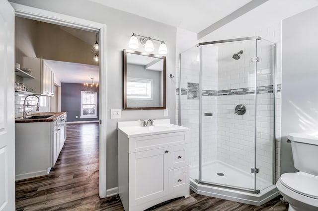 bathroom with toilet, vanity, vaulted ceiling, wood-type flooring, and a shower with shower door